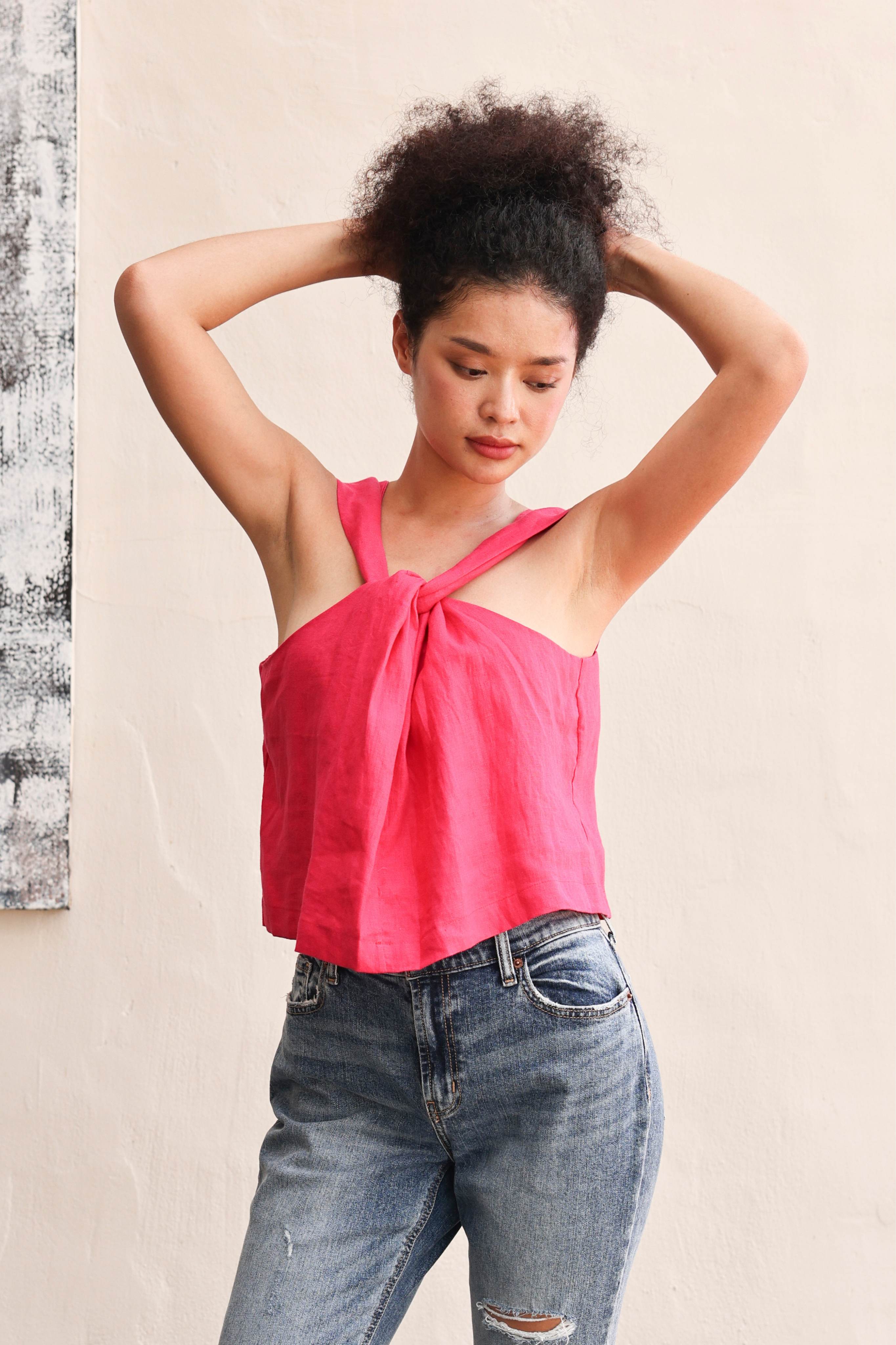 Woman wearing a pink top and blue jeans against a plain background