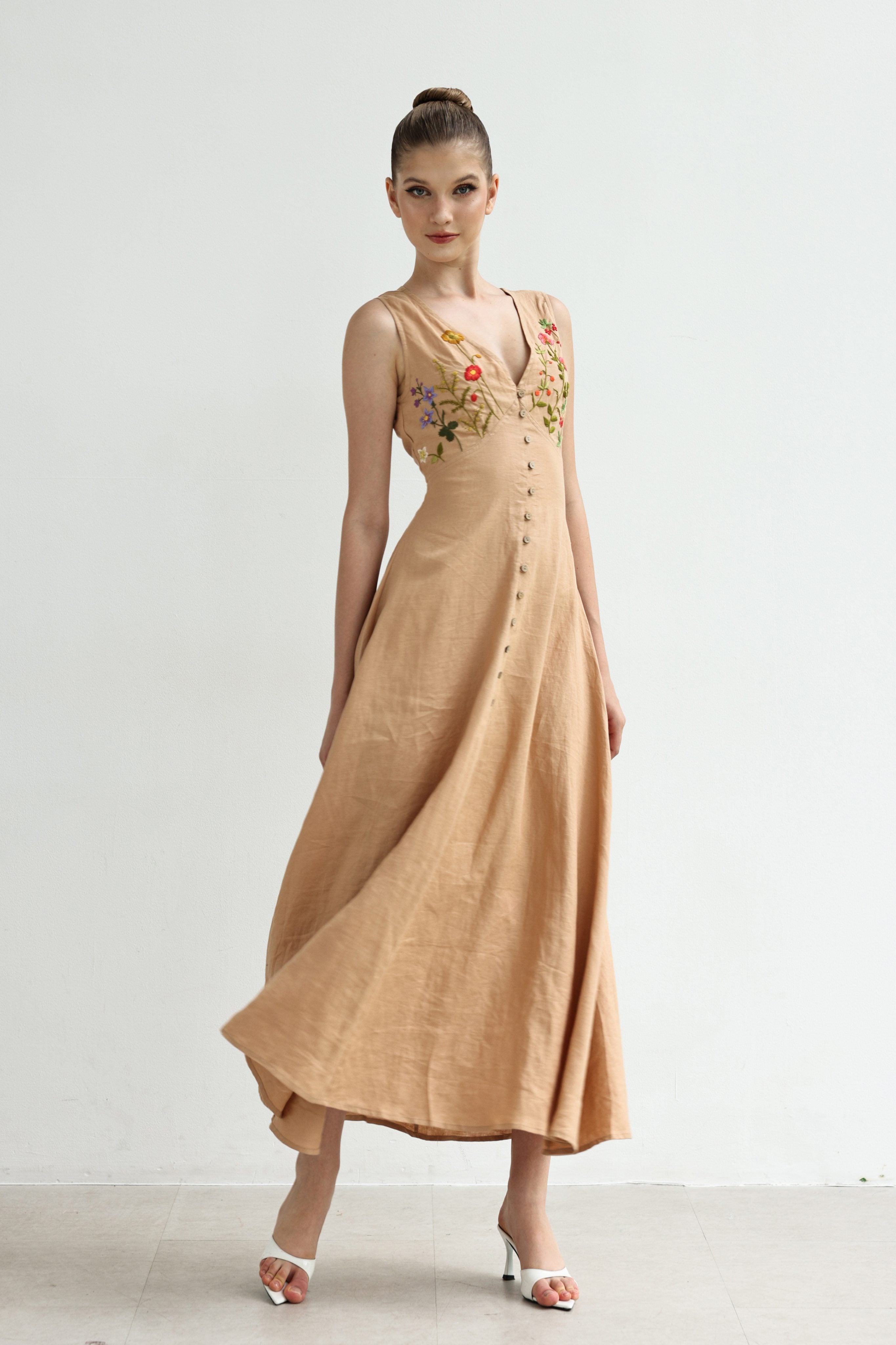 Woman wearing a dress with floral embroidery on a white background