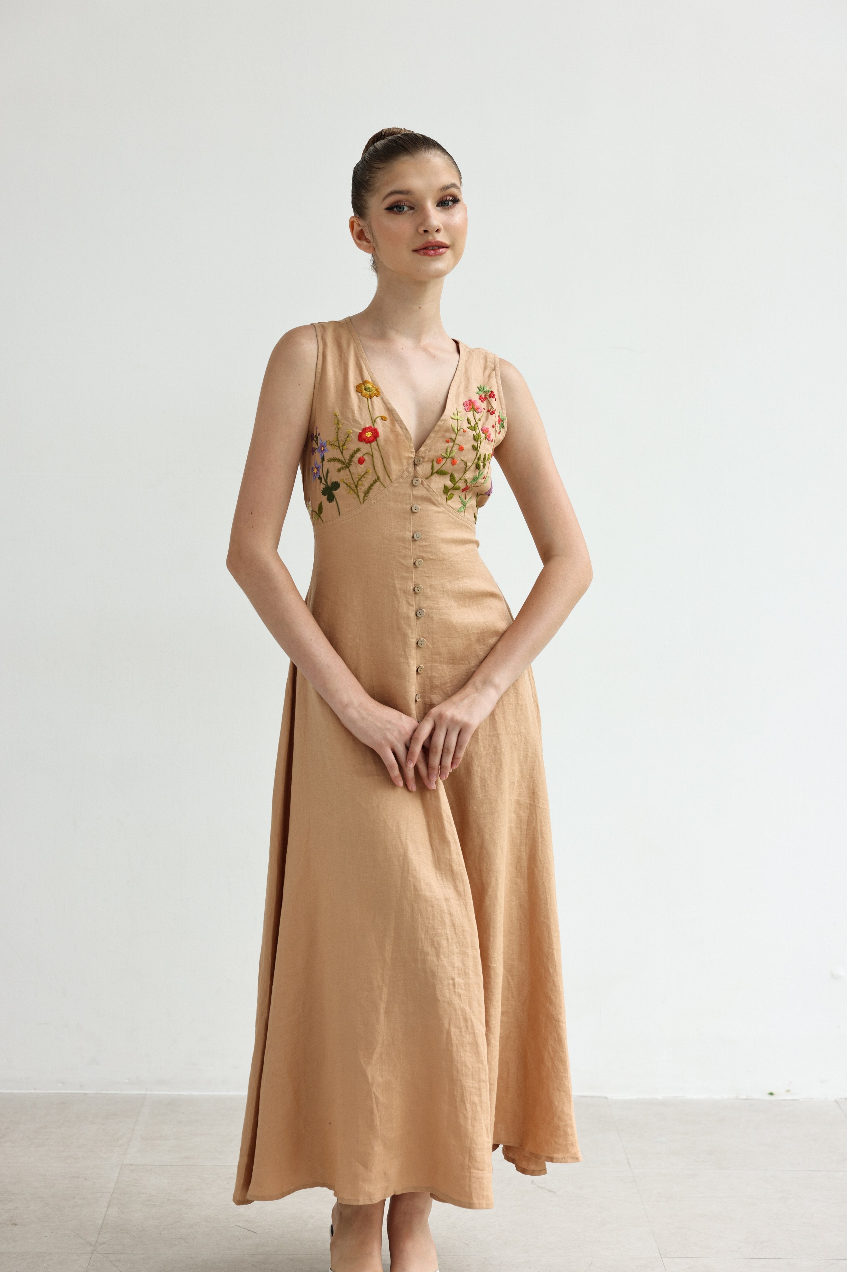 Woman wearing a dress with floral embroidery on a white background