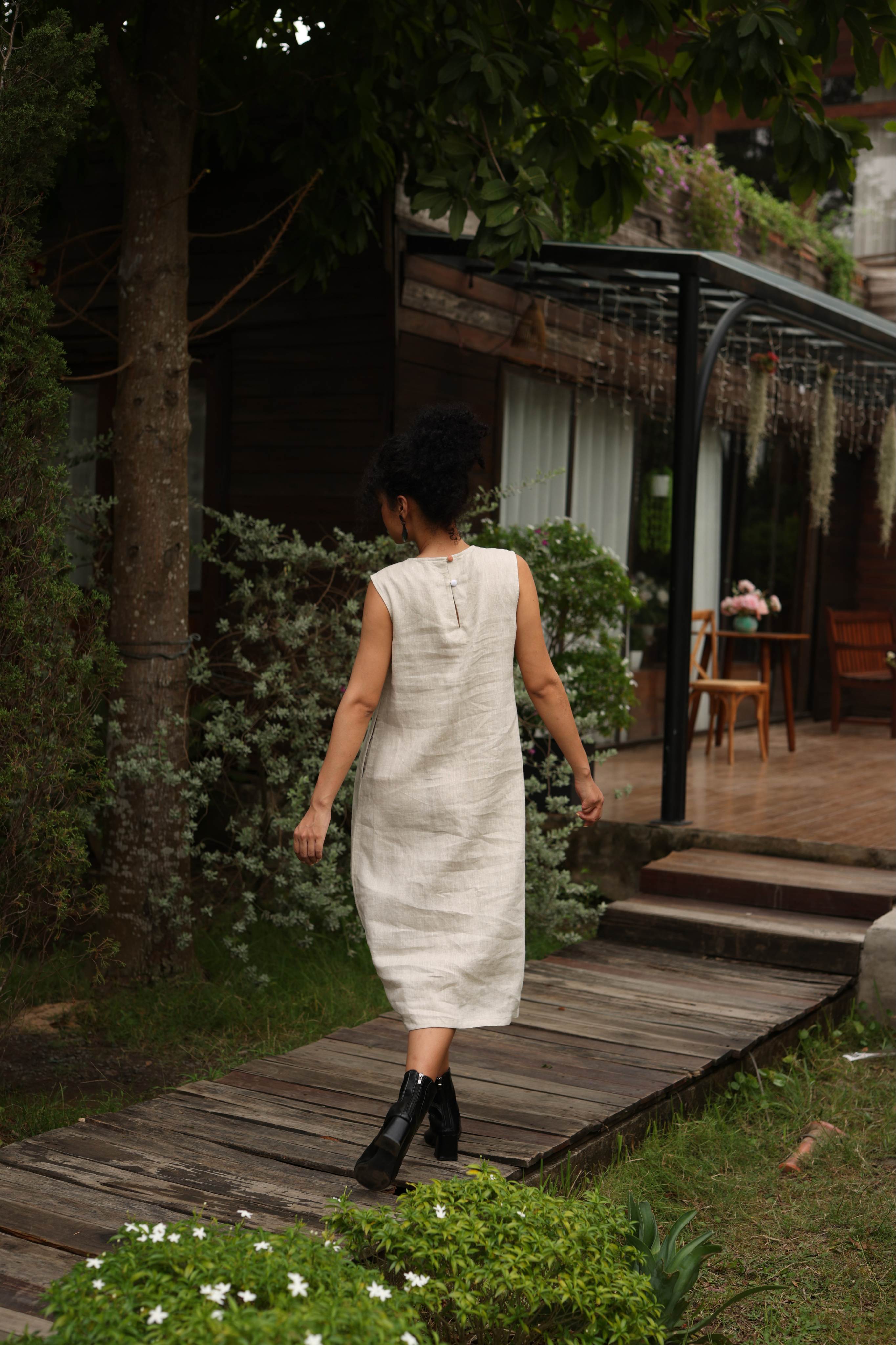 Woman in a dress walking on a wooden path in a garden setting