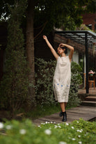 Woman in a dress standing on a wooden path with greenery around