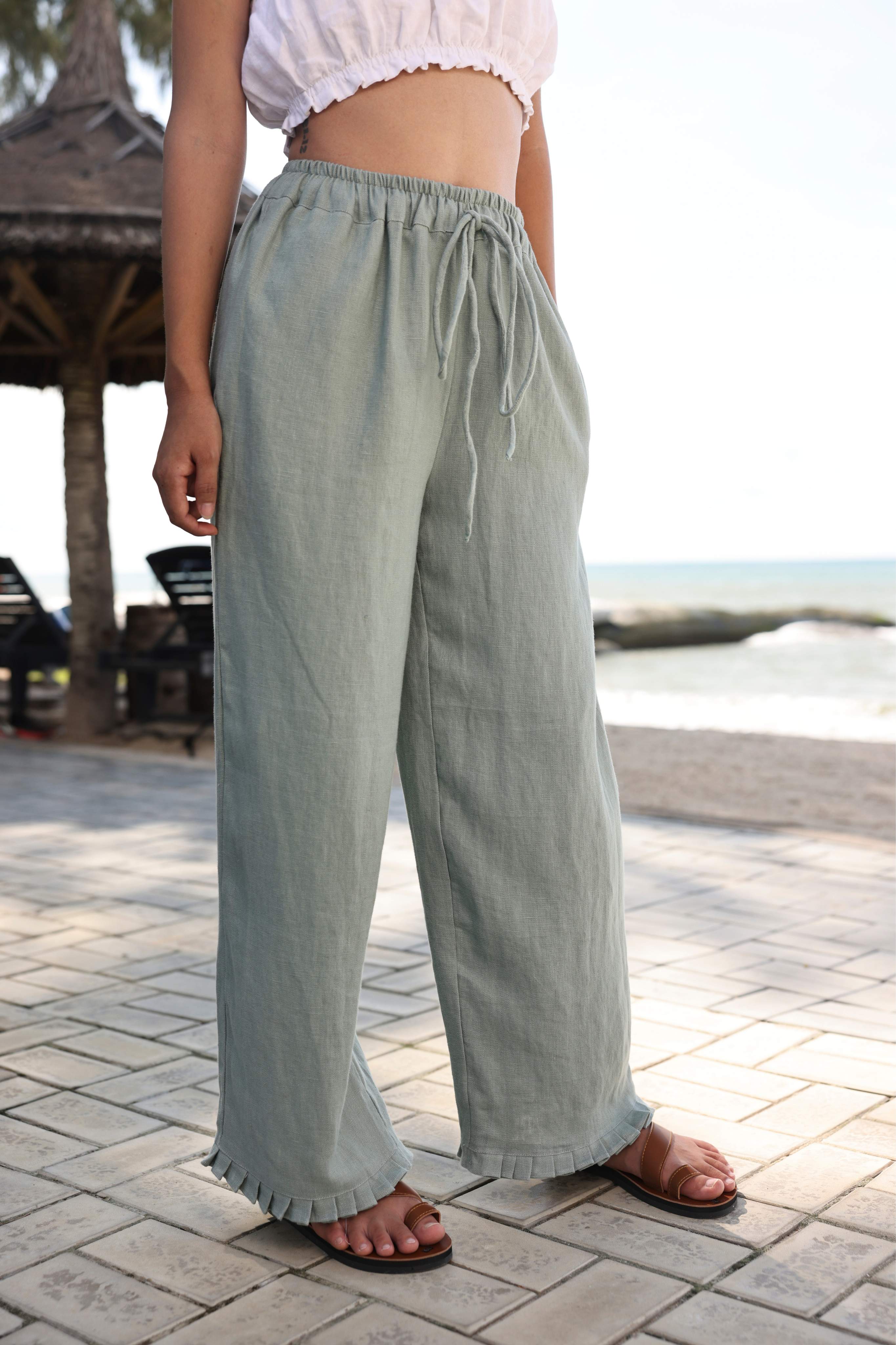 Person wearing light green pants standing on a paved area with a blurred background