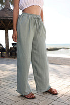 Person wearing light green pants standing on a paved area with a blurred background