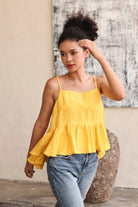 Woman wearing a yellow top and blue jeans against a neutral background