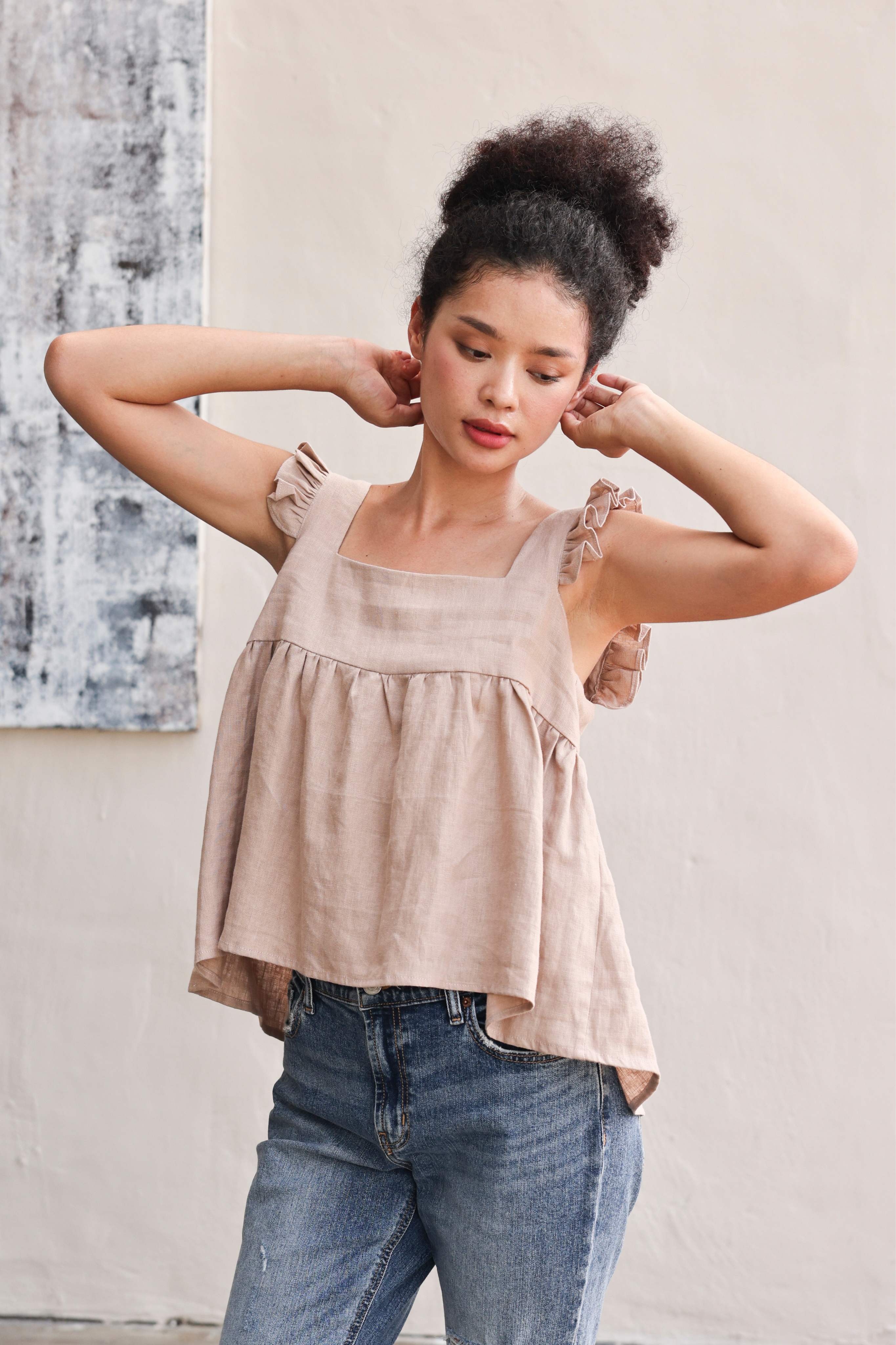 Woman wearing a top and blue jeans against a neutral background