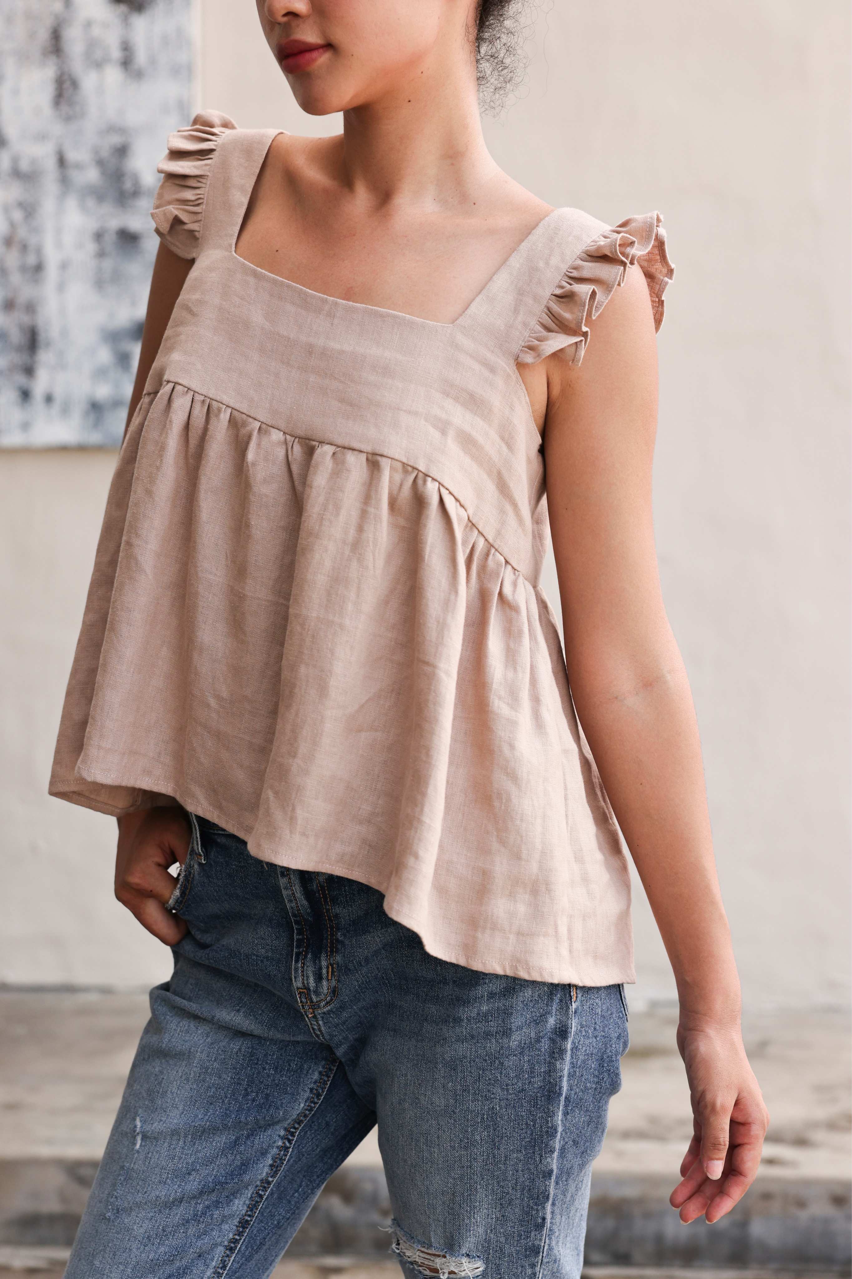 Woman wearing a top and blue jeans against a neutral background