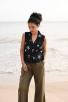 Woman wearing a black floral embroidered vest on a beach