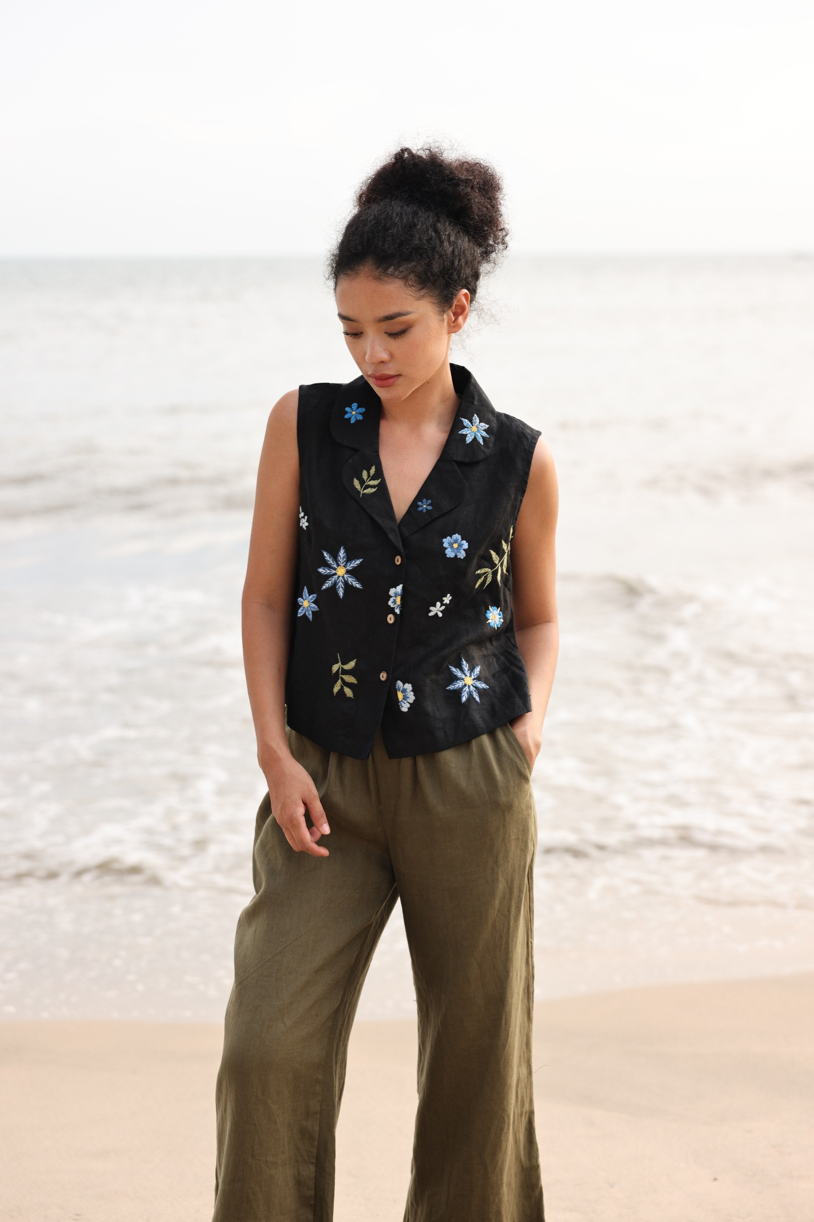 Woman wearing a black floral embroidered vest on a beach