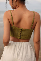 Person wearing a green crop top with button details and beige shorts outdoors.