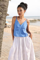 Woman wearing a blue top and white skirt on a beach