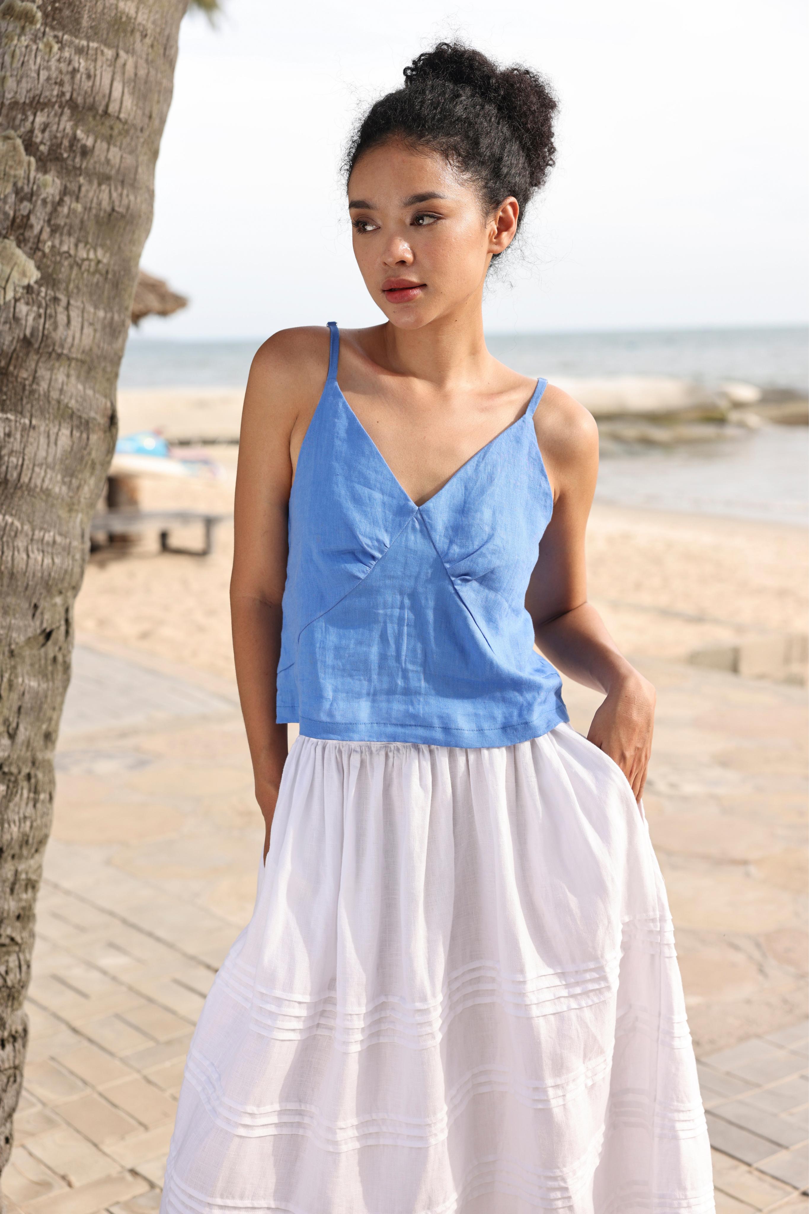 Woman wearing a blue top and white skirt on a beach