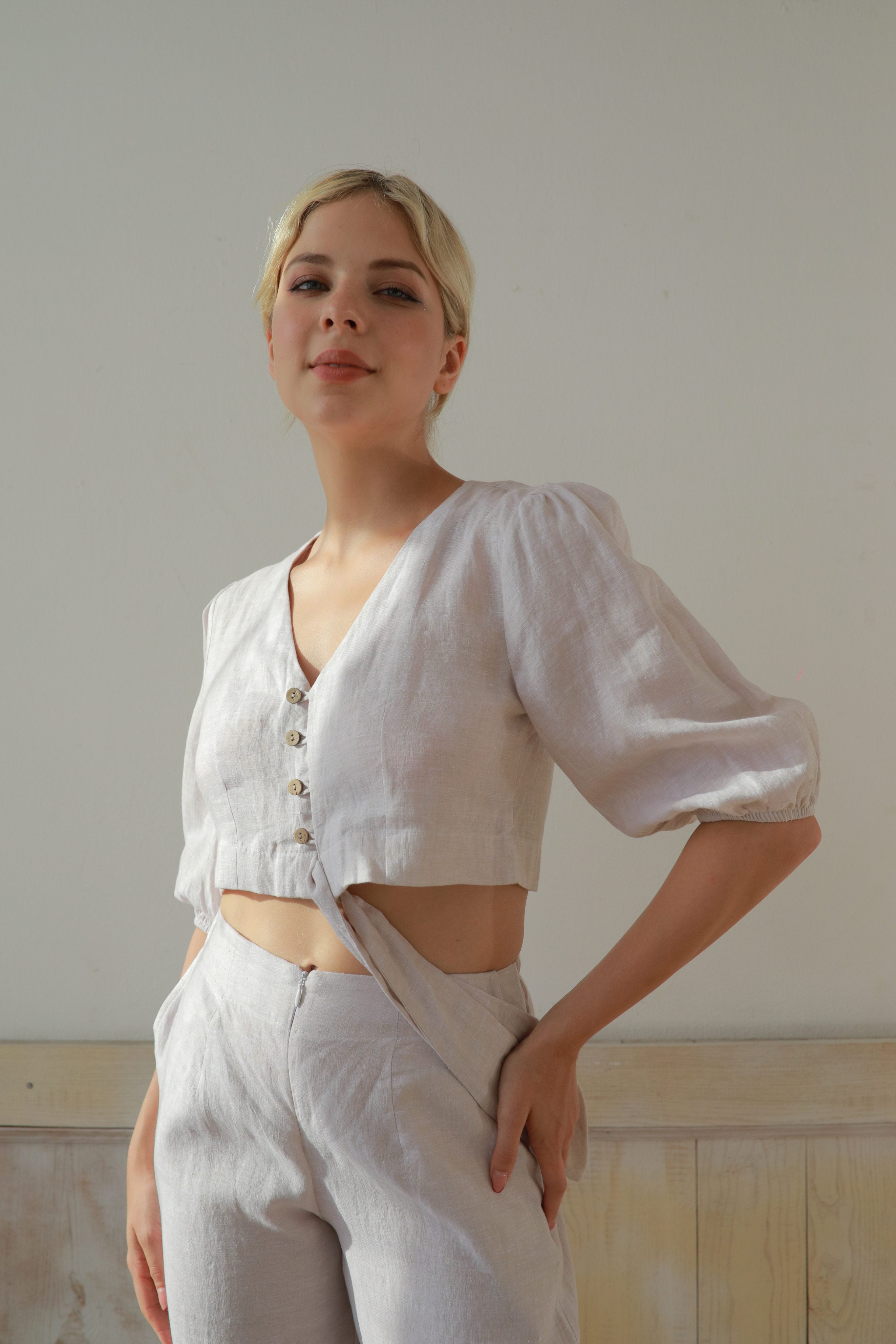 Woman wearing a white outfit with puffed sleeves against a plain background