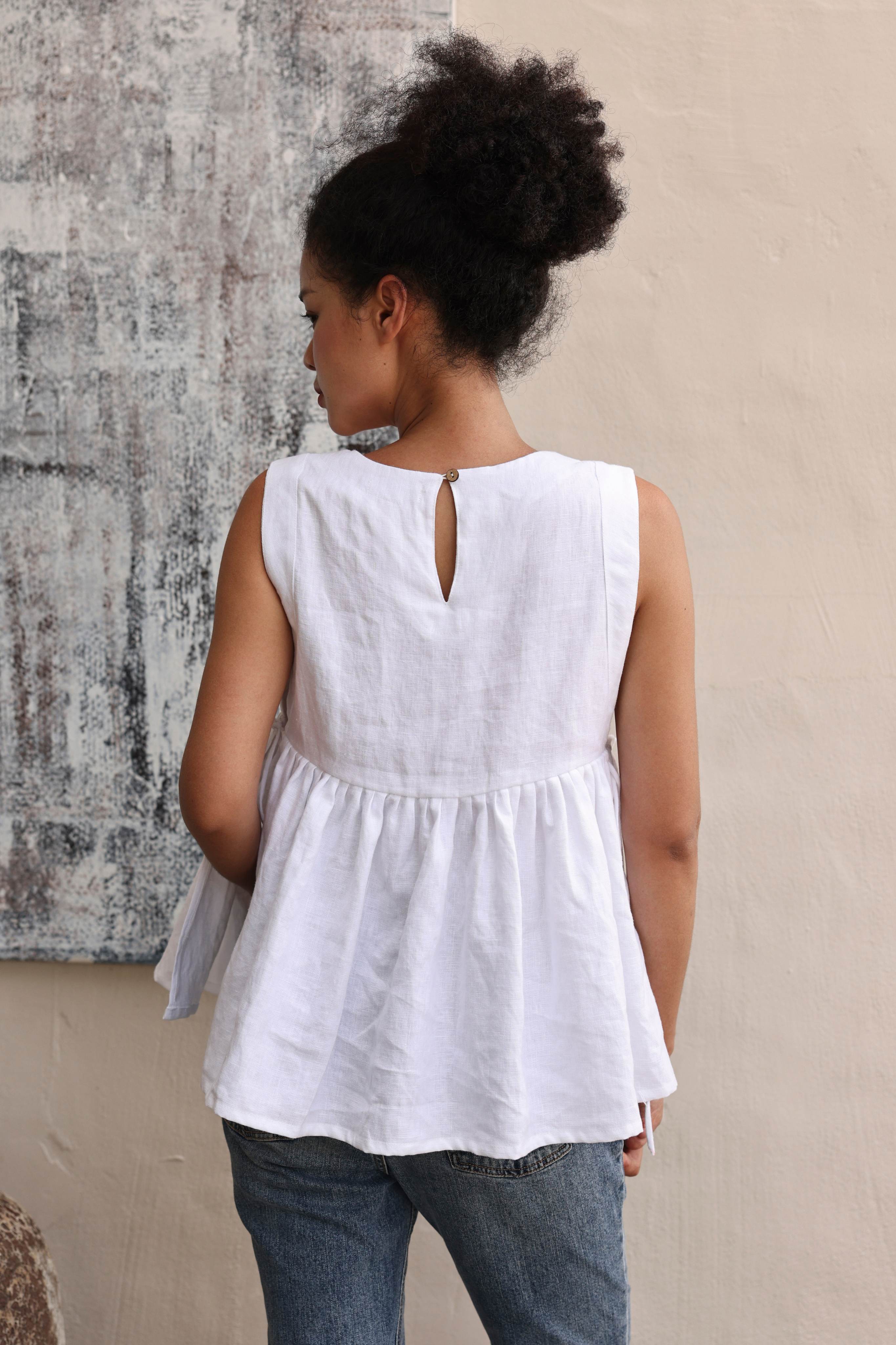 Person wearing a white sleeveless top with a textured wall background