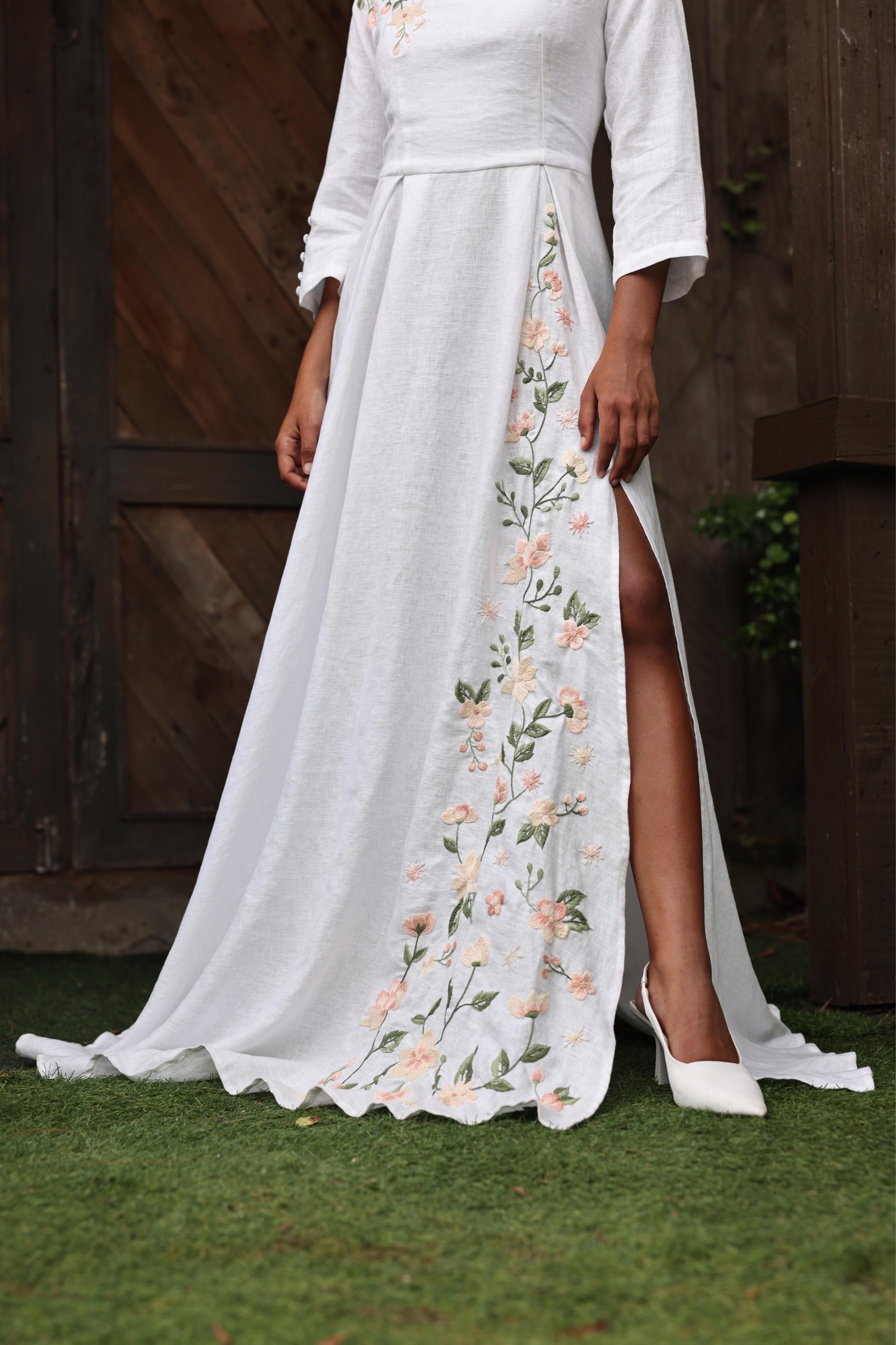 White dress with floral embroidery on a person standing outdoors.