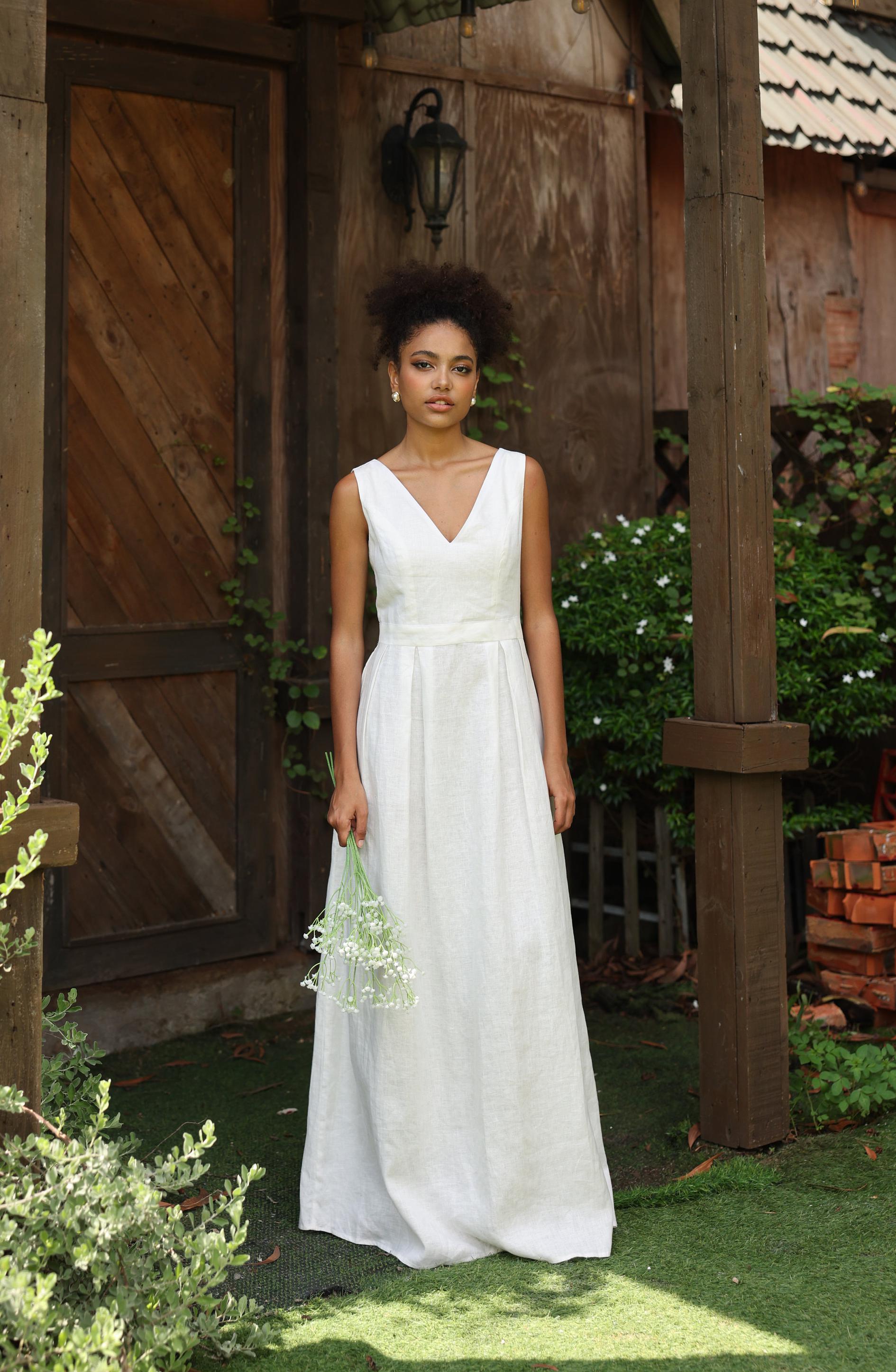 Woman in an ivory dress standing outdoors near a wooden building