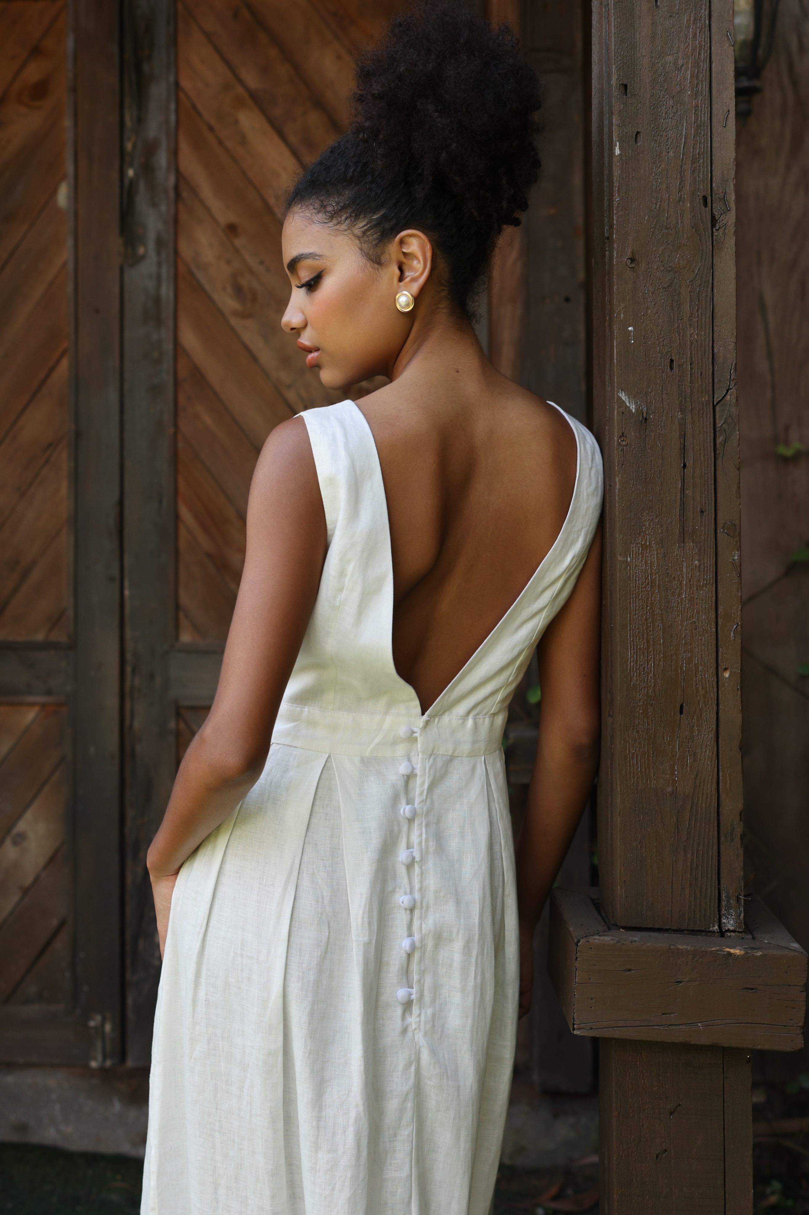 Woman in an ivory dress standing outdoors near a wooden door.
