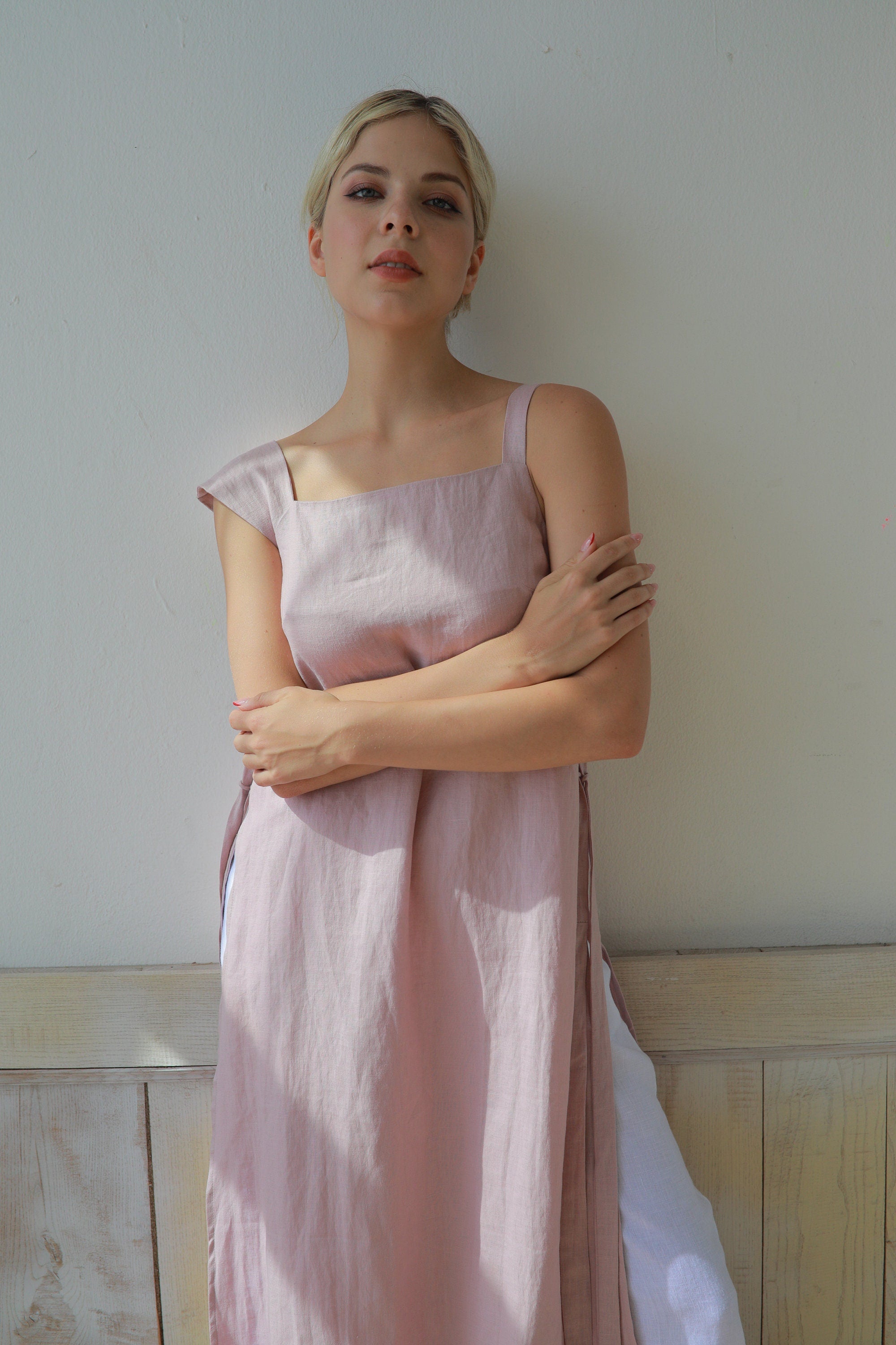 Woman wearing a light pink dress against a plain wall.