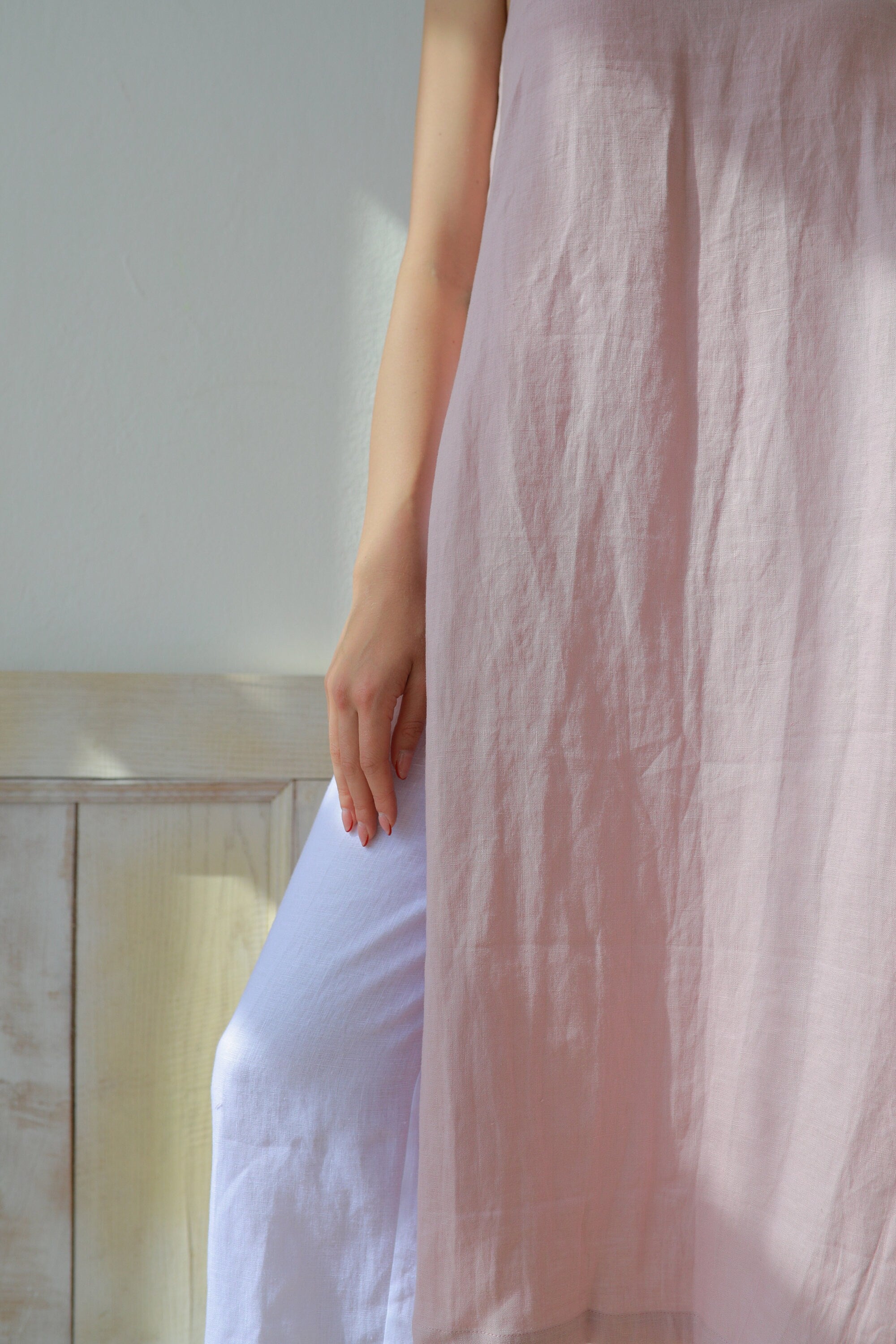 Person wearing a light pink sleeveless dress with a blurred background