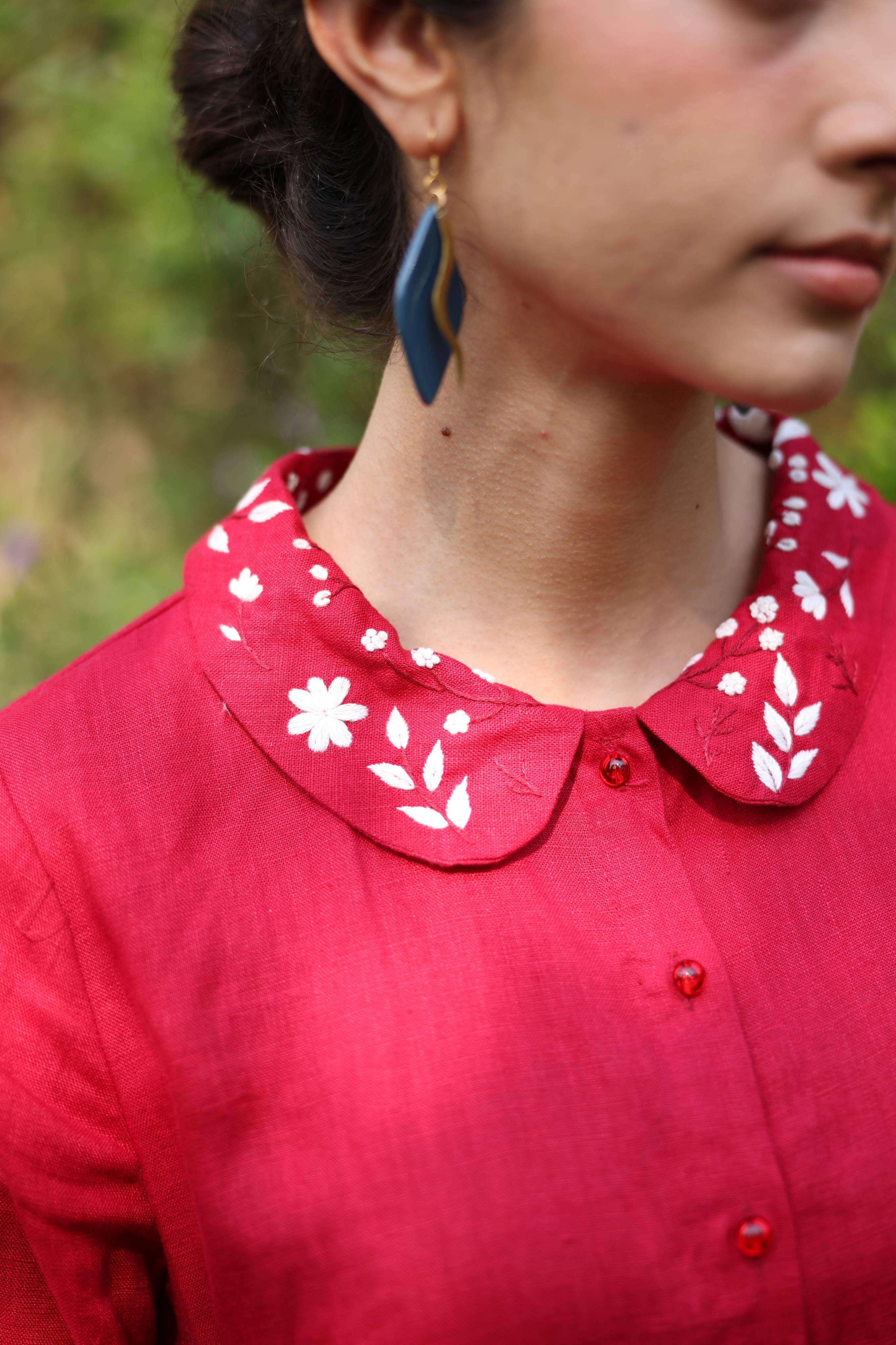 Close-up of a person wearing a red dress with a white floral collar.