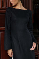 Woman wearing a black dress with long sleeves in an indoor setting.