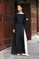 Woman wearing a black long-sleeve dress standing in front of a wooden door.