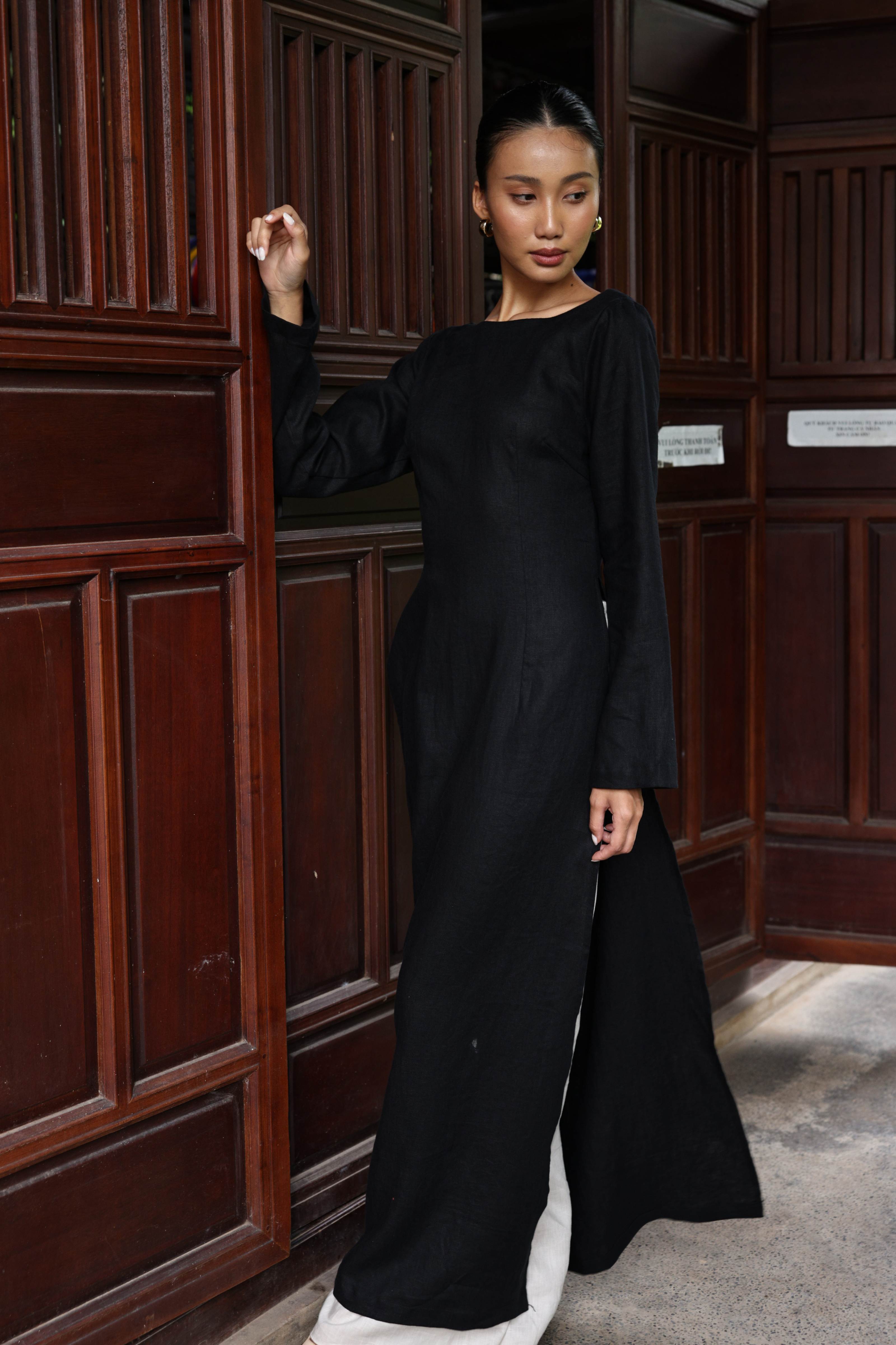 Woman in a black outfit standing in a room with wooden paneling.