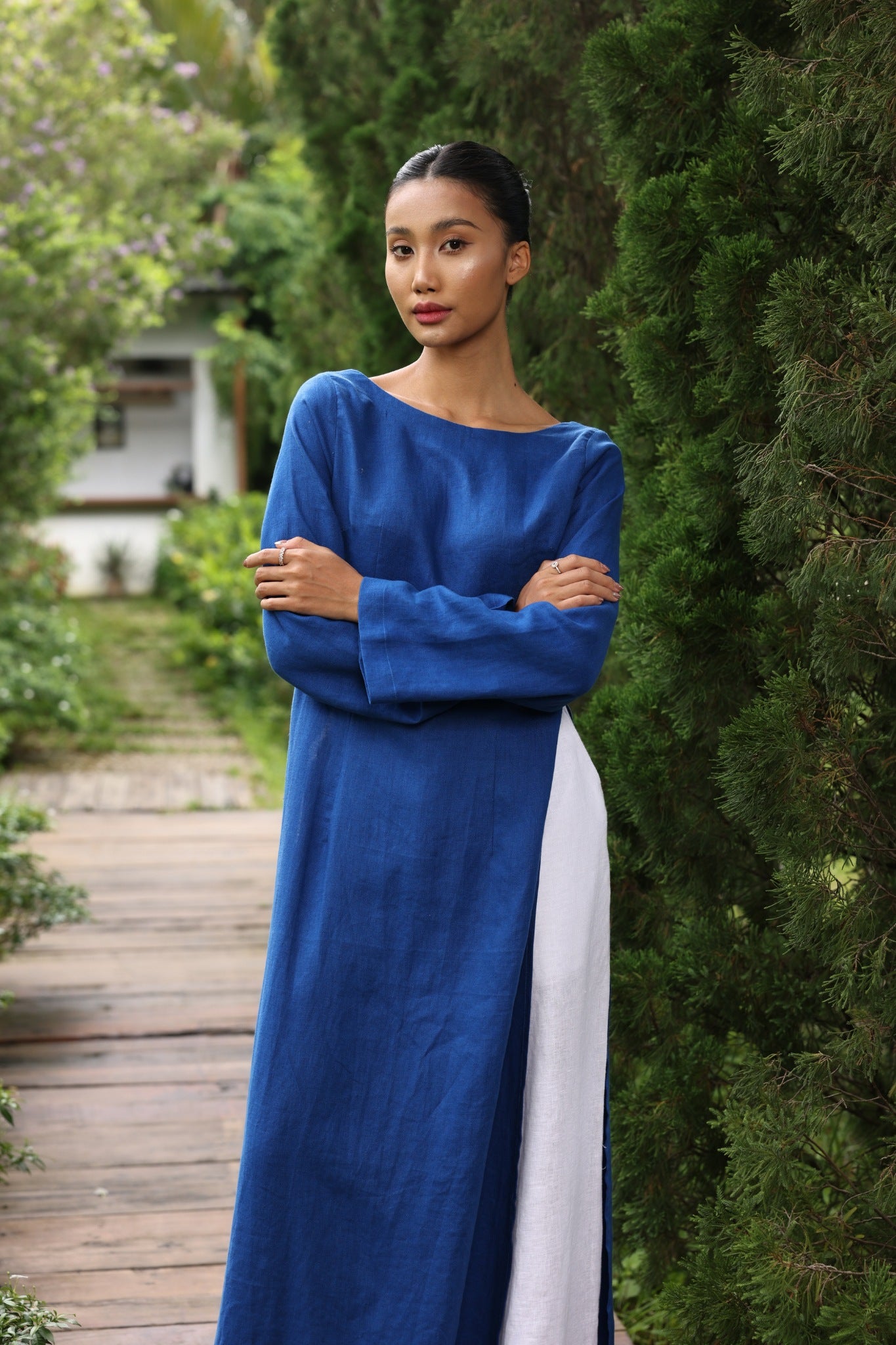 Woman in a blue dress standing outdoors with greenery around