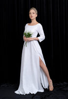 Woman in a white dress holding flowers against a black background