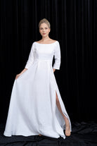 Woman wearing a white dress with 3/4 sleeves against a black background