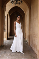 Woman in a white dress standing in an arched stone corridor