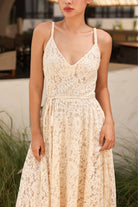 Woman wearing a beige lace dress in an outdoor setting