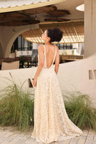 Woman in a lace dress standing in an outdoor setting with plants and tables.