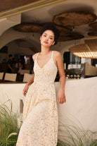 Woman in a white lace dress standing in an outdoor setting with hanging lights.