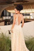 Woman in a lace dress standing outdoors with plants and a building in the background