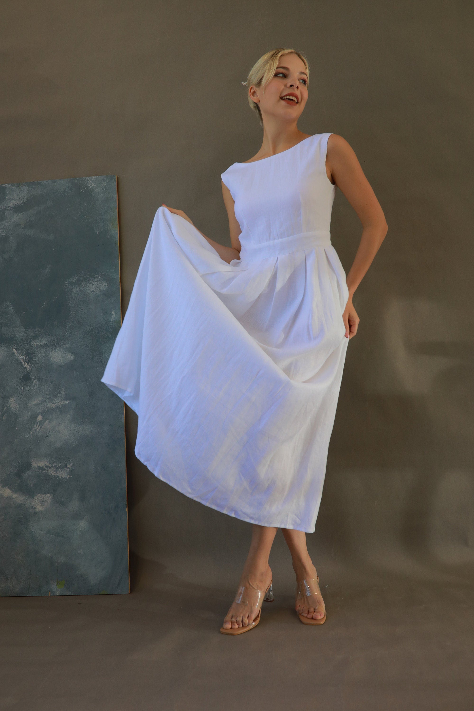 Woman in a white dress standing against a plain background