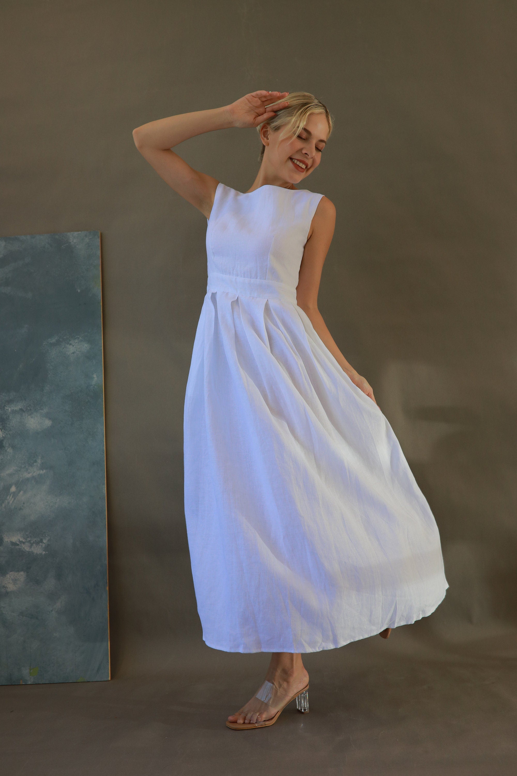 Woman in a white dress standing against a plain background
