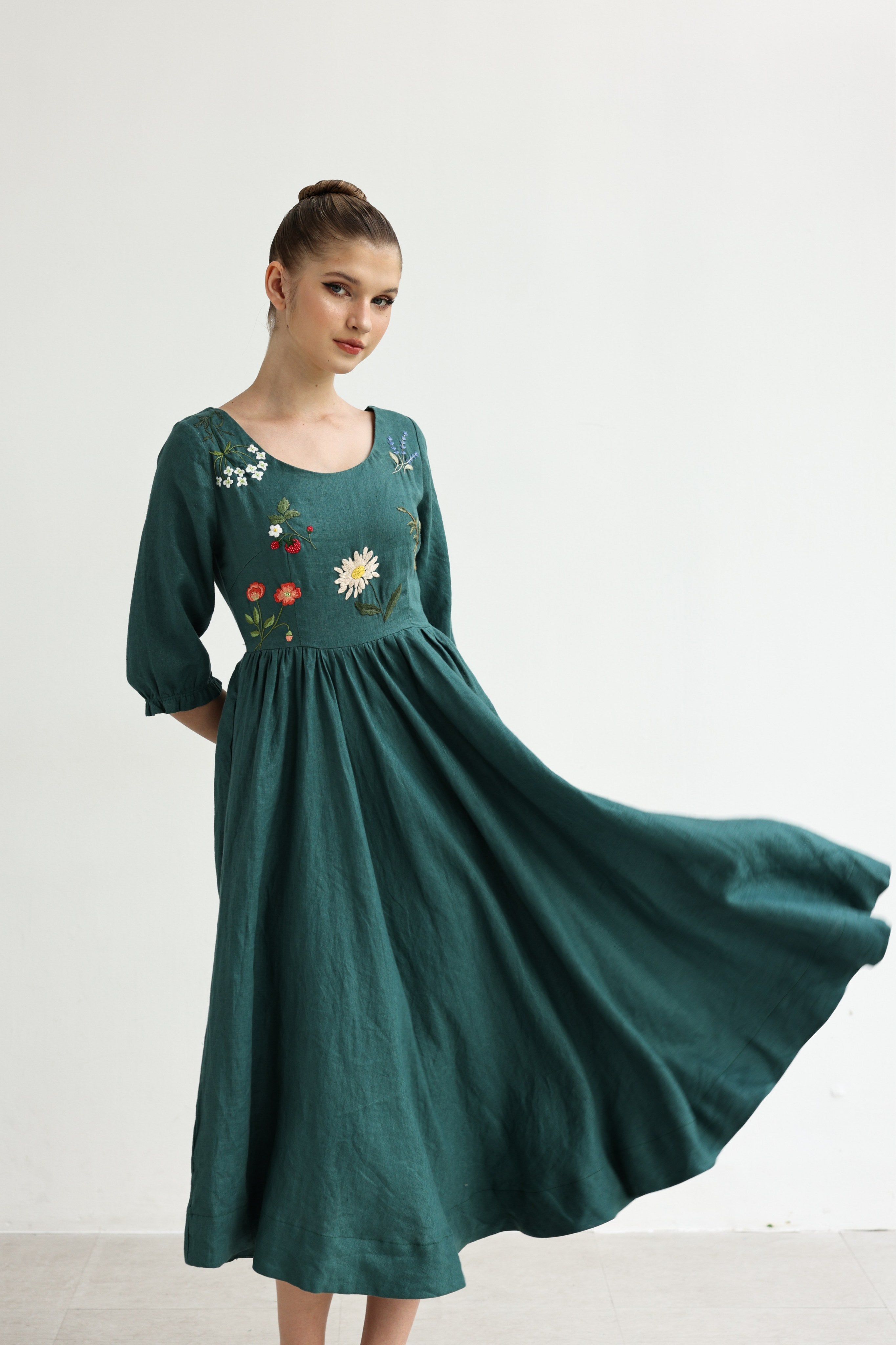 Woman wearing a green dress with floral embroidery on a white background