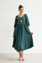 Woman wearing a green dress with floral embroidery on a white background