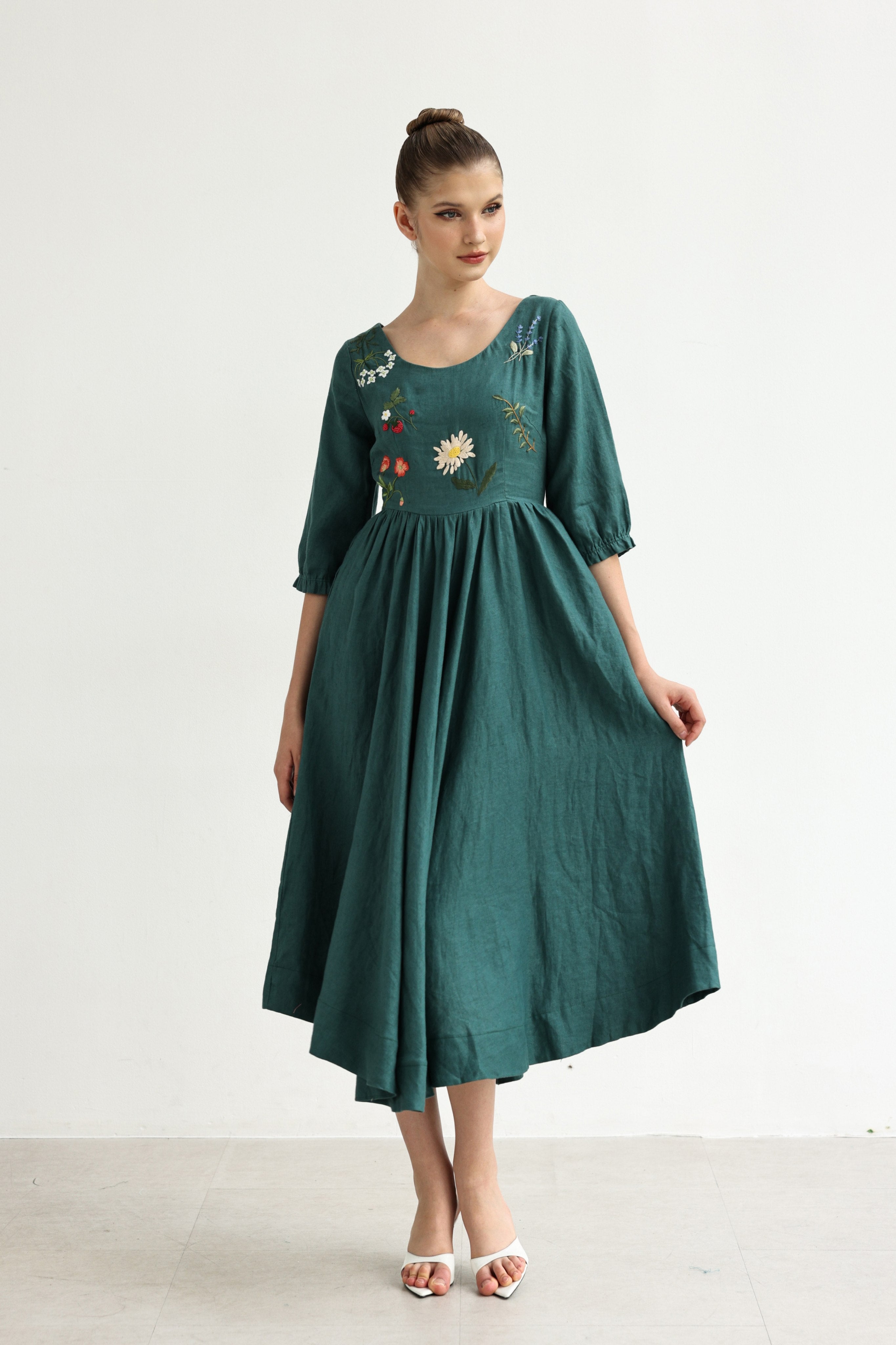 Woman wearing a green dress with floral embroidery on a white background