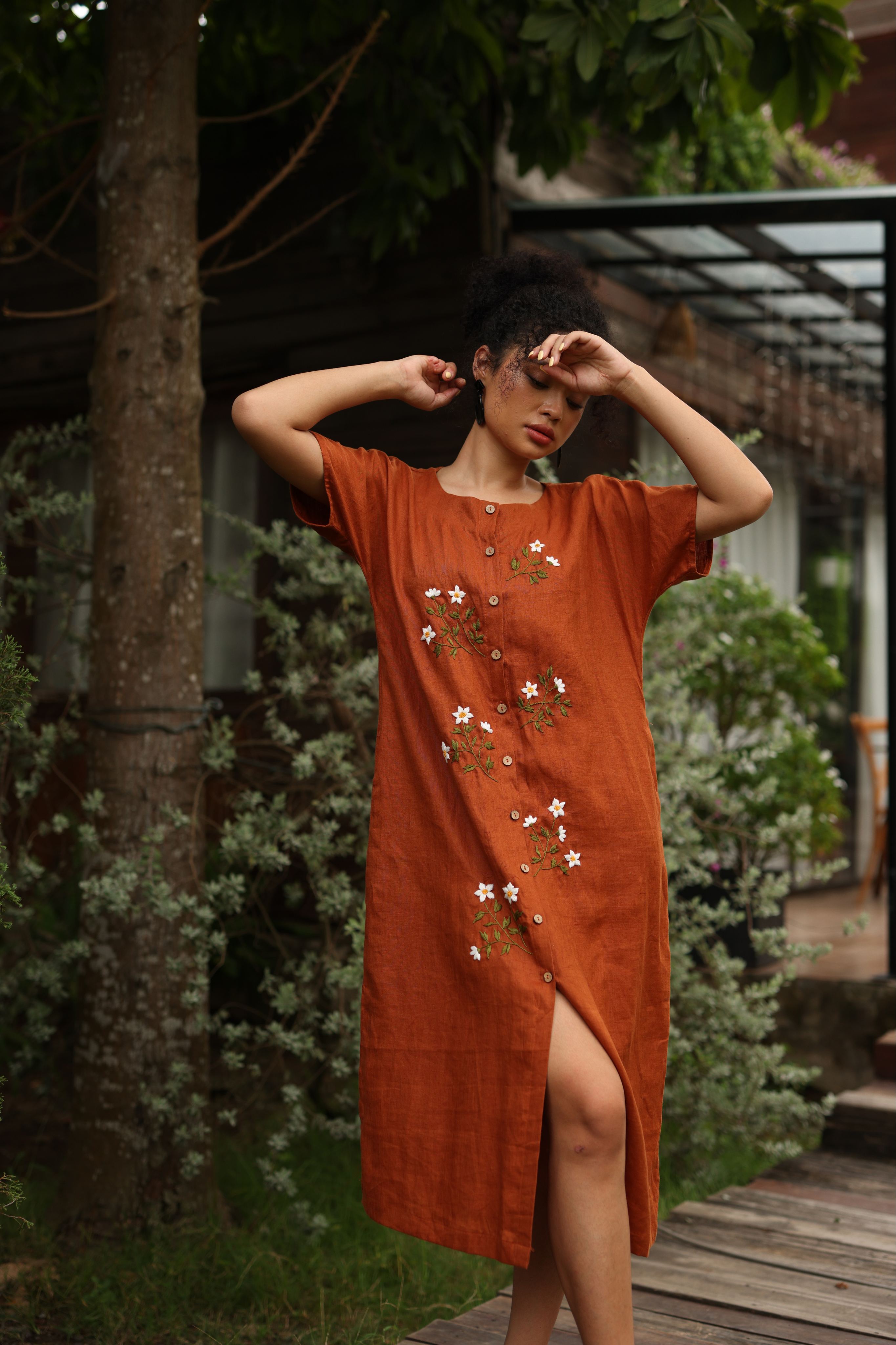 Woman wearing a dress with floral embroidery in a garden setting