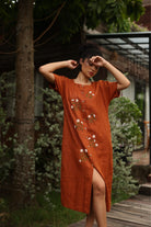 Woman wearing a dress with floral embroidery in a garden setting