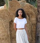 Woman in a white outfit standing in front of hay bales