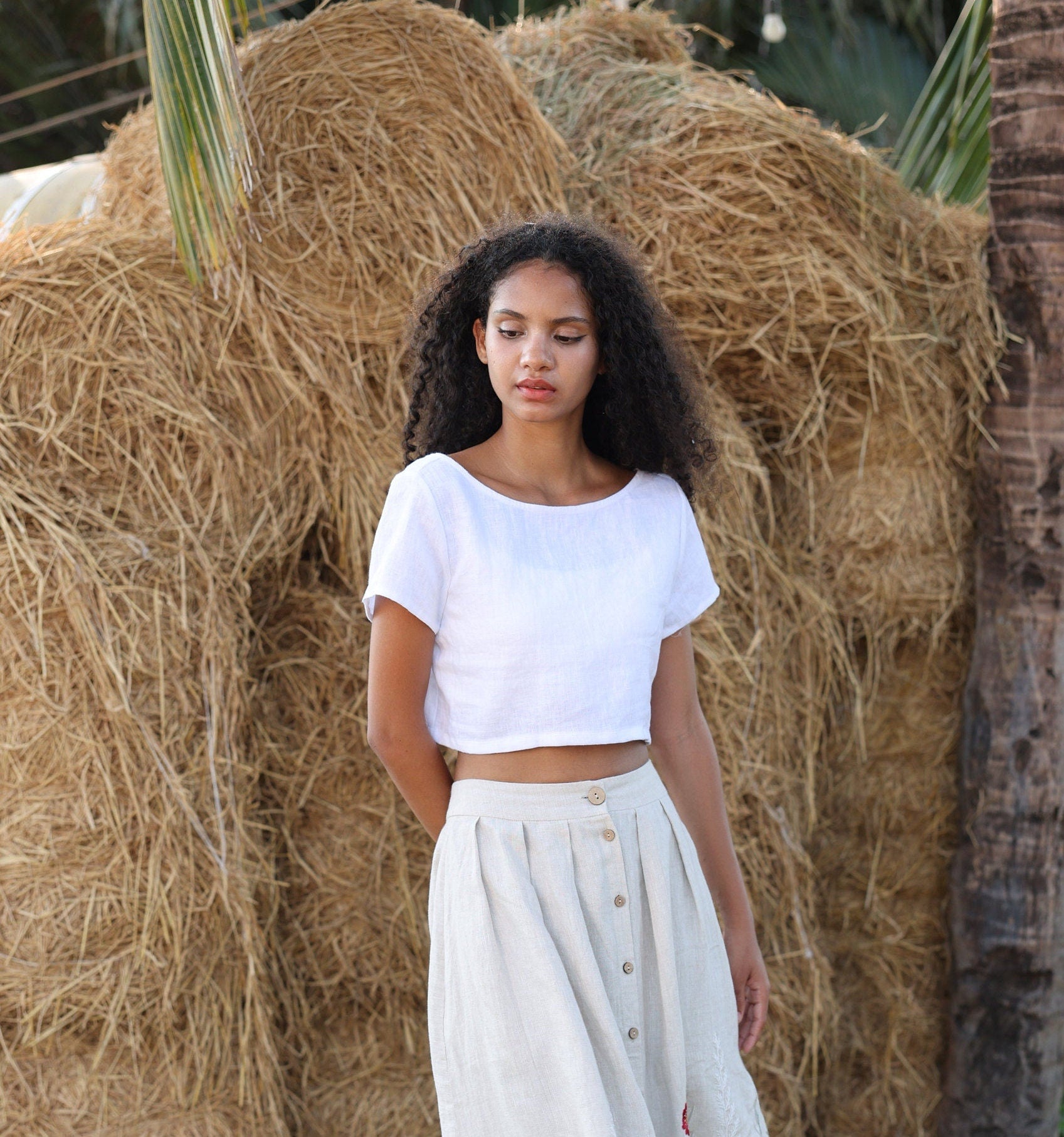 Woman in a white outfit standing in front of hay bales