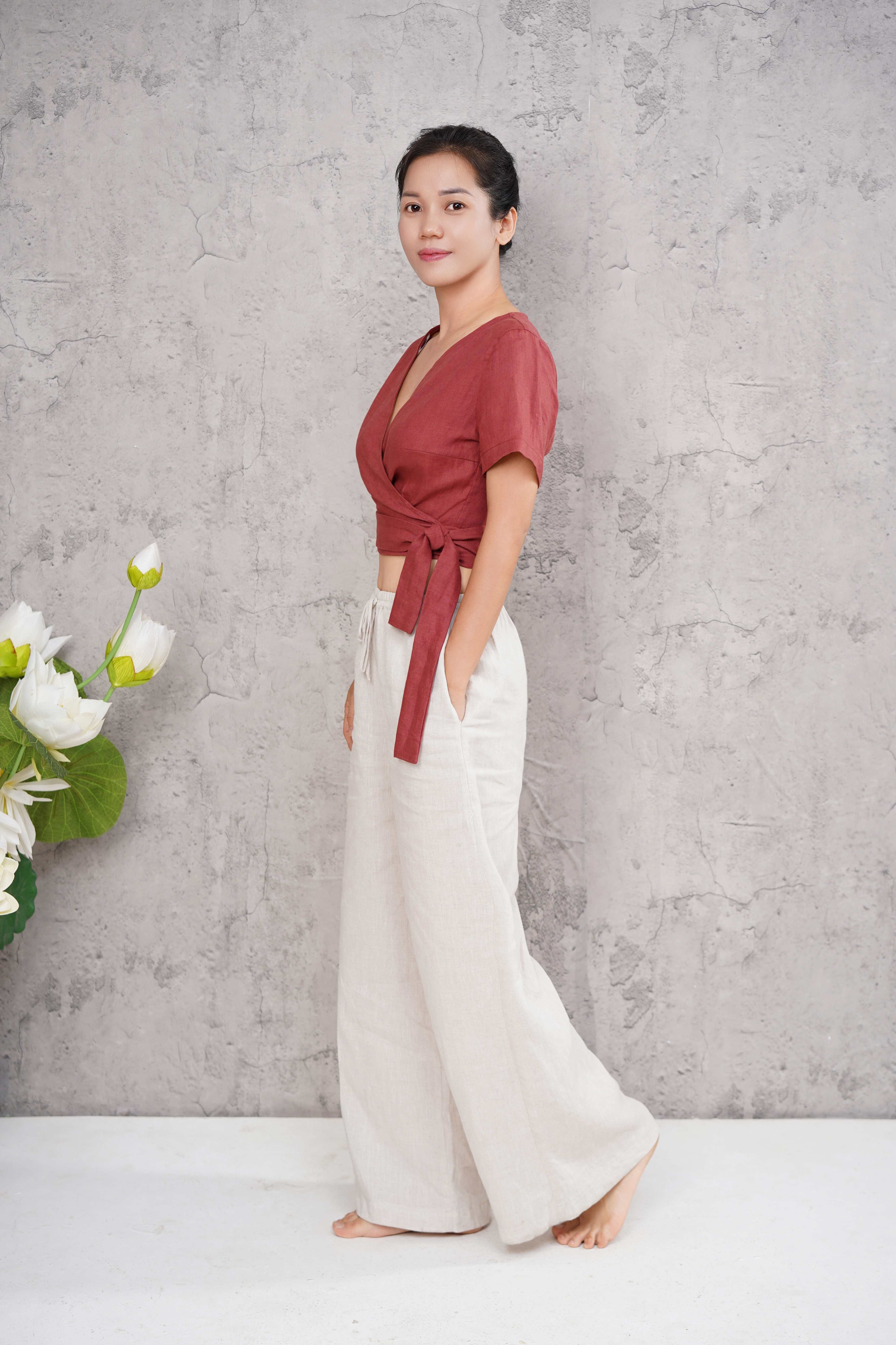 Woman wearing a red top and white pants against a gray background