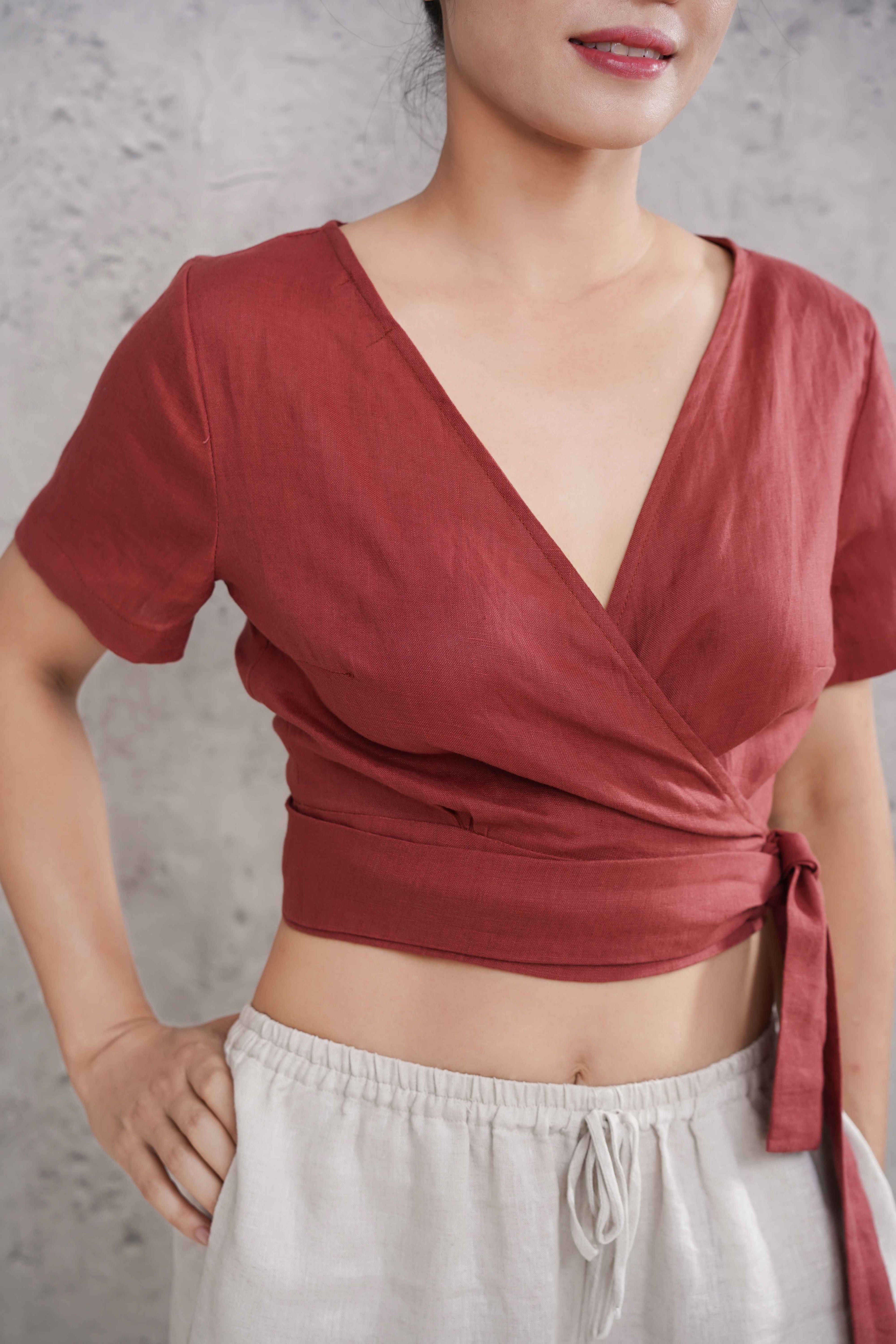 Person wearing a red wrap top with a neutral background