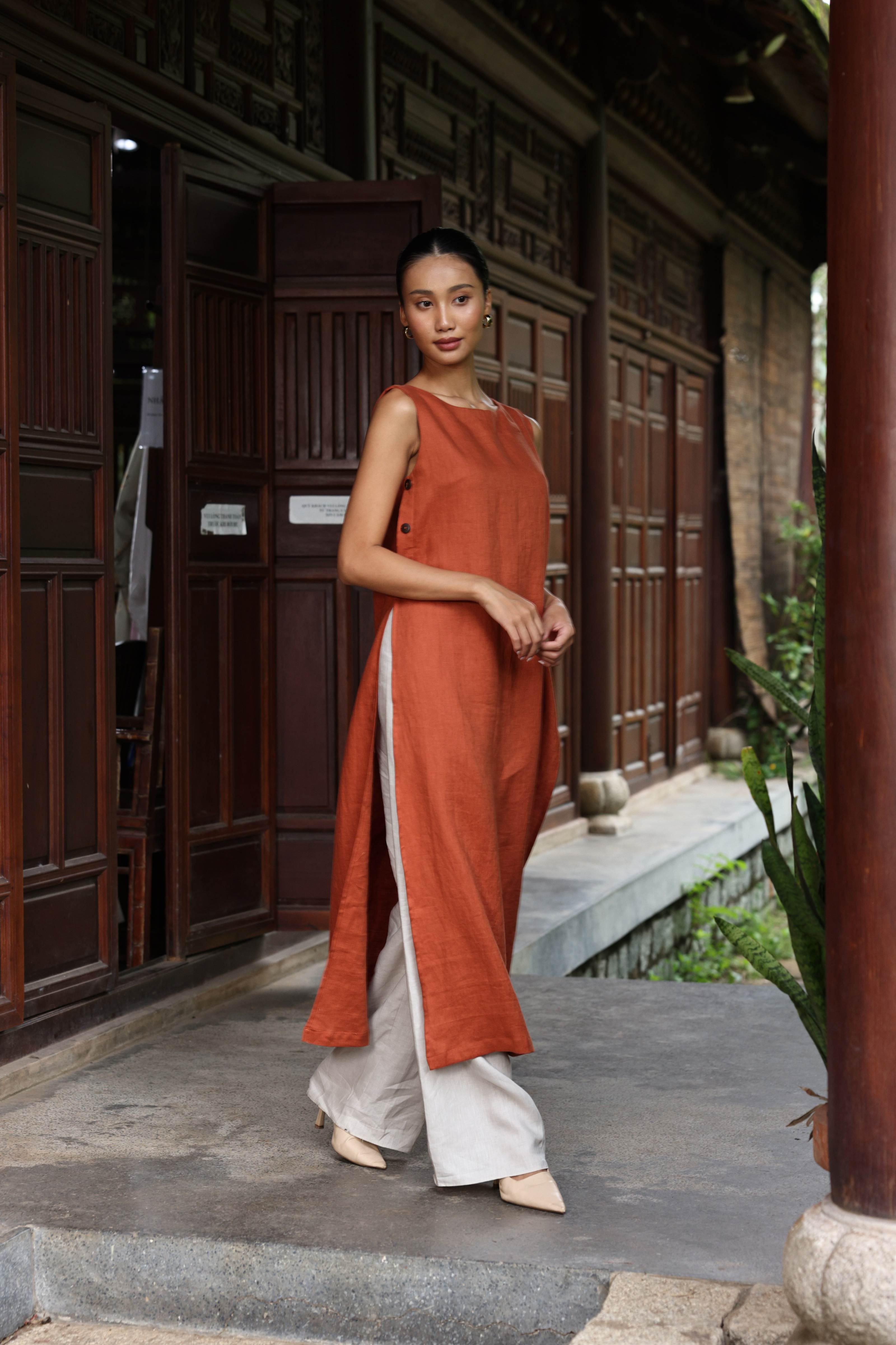 Woman in a rust-colored dress standing in front of a traditional building.