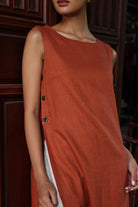 Woman wearing a rust-colored dress with buttons on a dark background