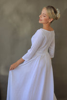 Woman wearing a white dress with 3/4 sleeves against a neutral background