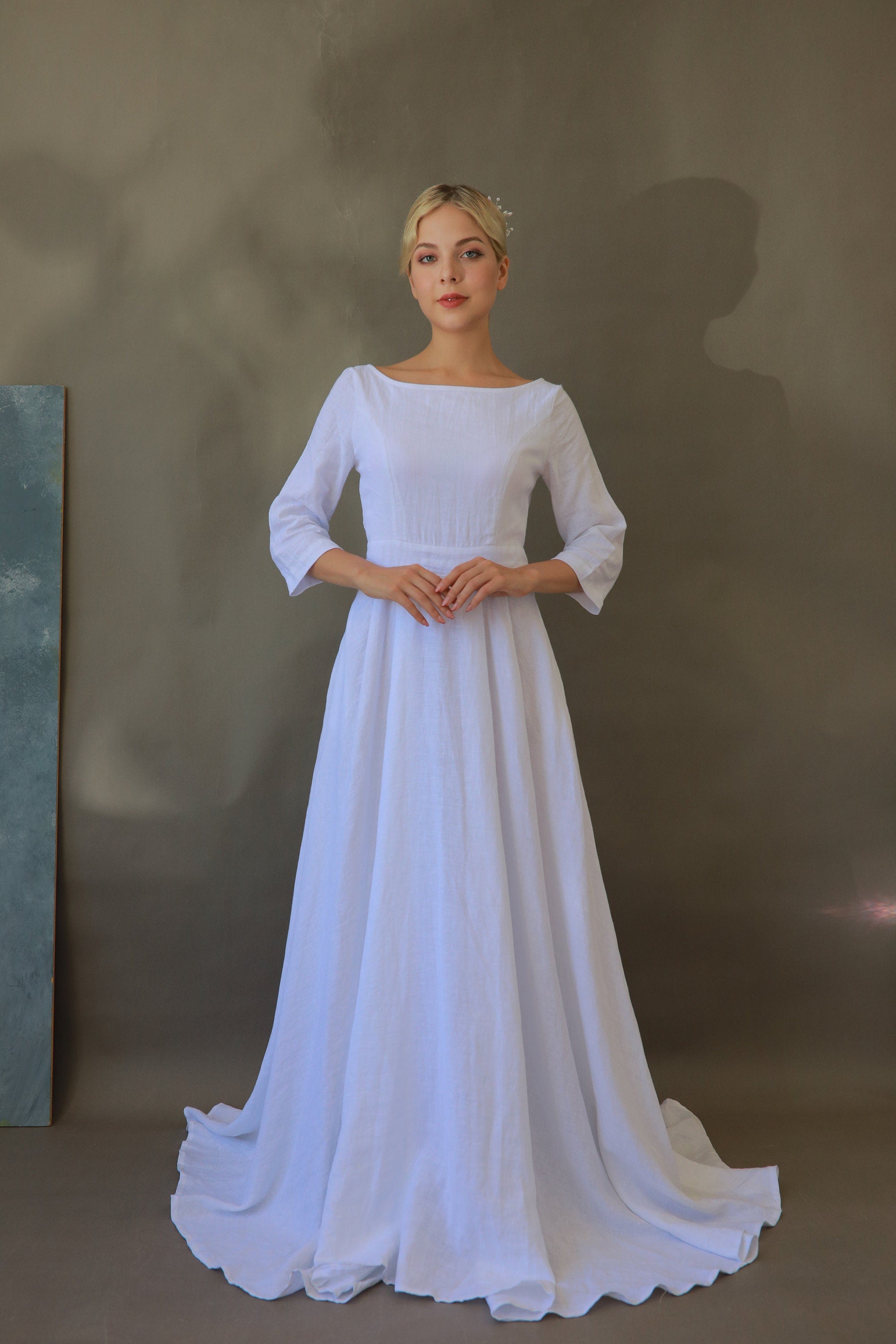 Woman wearing a white wedding dress against a plain background