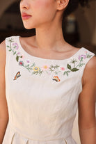 A sleeveless dress with floral embroidery and butterfly designs on a blurred background